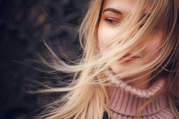 Woman utilizing professional-grade hair straightener and curler for achieving salon-quality styling at home