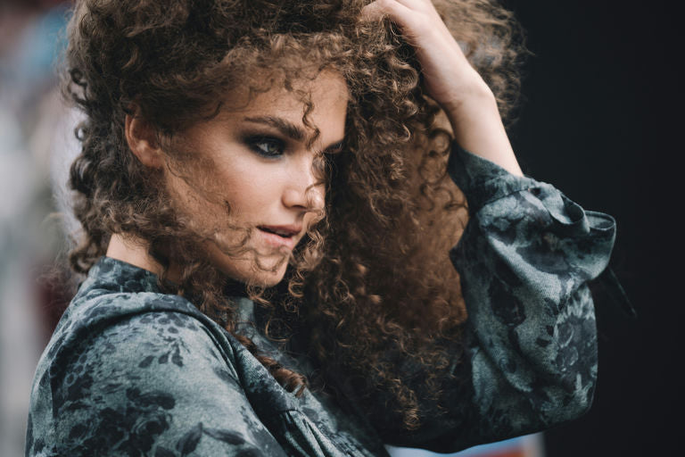 Woman using professional hair appliances like straightener and curler for home hair care and hairstyle transformations