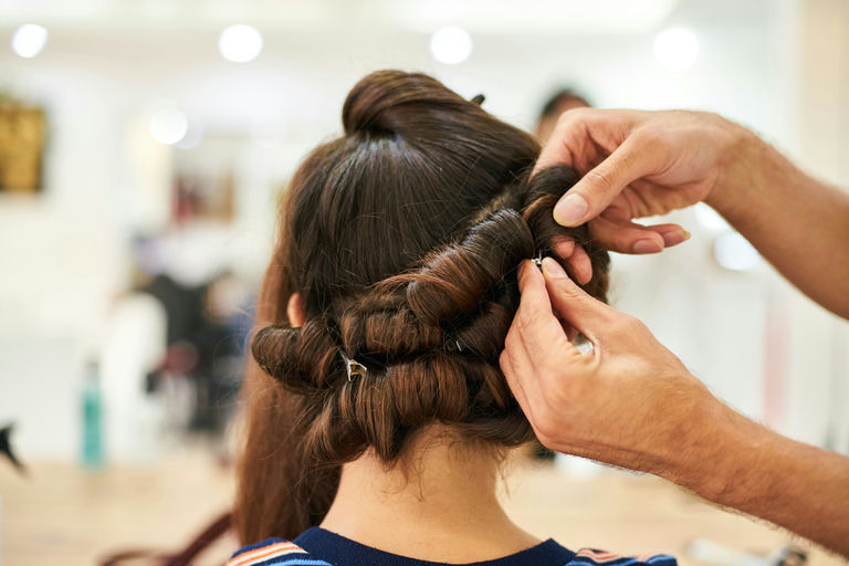 Woman using hair straightener and curling iron for perfect hairdo as suggested in hair care guide blog article